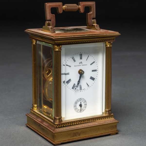 Reloj de Viaje Matthew Norman con estructura en metal dorado y cristales biselados. Siglo XX