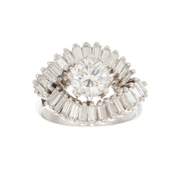 Sortija en oro blanco con diamante central talla brillante orlado por diamantes talla baguette. 