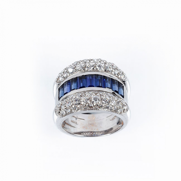 Sortija de alta joyer&iacute;a, en s&oacute;lida montura de oro blanco 18 K, con motivo en banda central de zafiros finos azules y blancos diamantes 