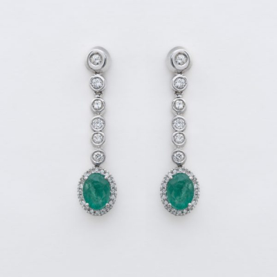 Pendientes largos en oro blanco con l&iacute;nea y roset&oacute;n de diamantes talla brillante y esmeralda talla oval engastados en garras y chat&oacute;n.