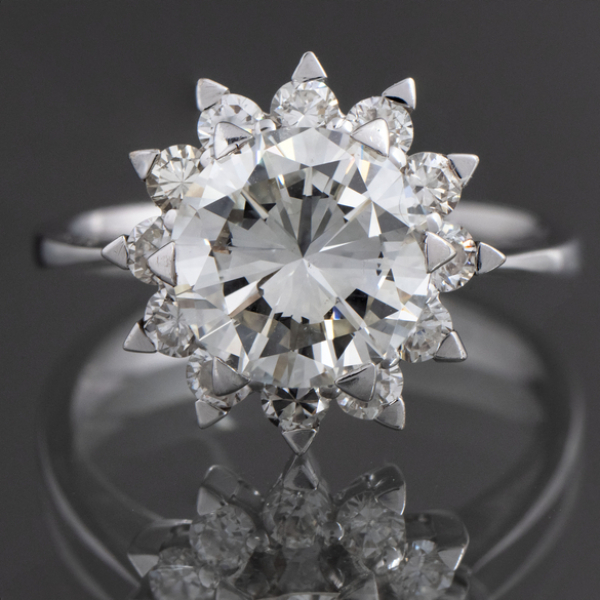 Anillo solitario con brillante central orlado de brillantes en oro blanco de 18 kt.