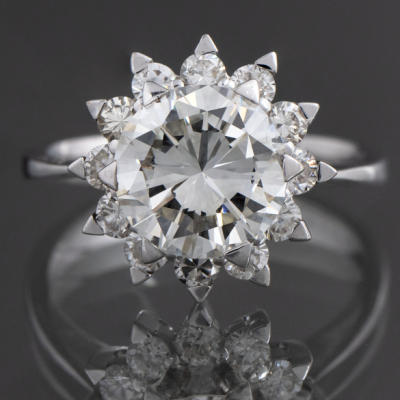 Anillo solitario con brillante central orlado de brillantes en oro blanco de 18 kt.