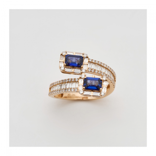 Sortija diseño cruzado en oro rosa con zafiros azules talla esmeralda y diamantes tallas brillante y baguette.