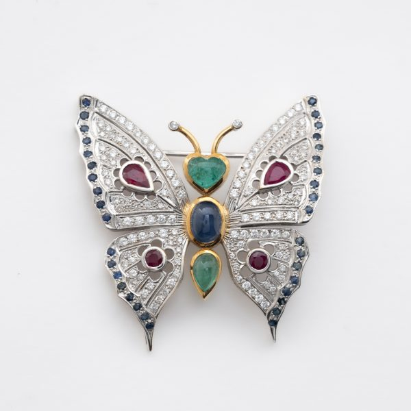 Broche diseño mariposa en oro bicolor, cuerpo con cabujones de esmeralda y zafiro azul tallas oval y corazón 
