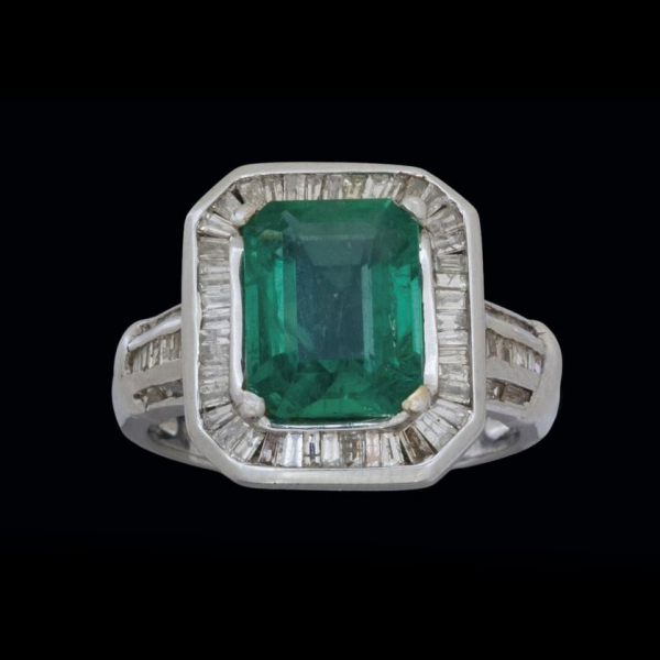 Anillo de oro blanco de 18 K. con esmeralda y diamantes calibrados.