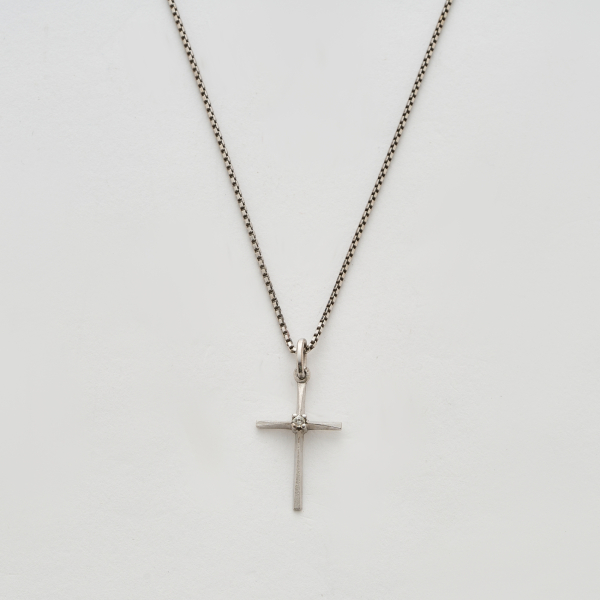 Colgante dise&ntilde;o cruz en oro blanco mate y brillo con un diamante talla brillante engastado en garras, 3 x 1,5 cm