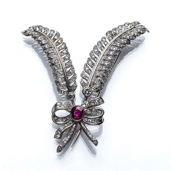 Original broche en forma de doble pluma con lazada, en montura de oro blanco cuajada de limpios y blancos diamantes