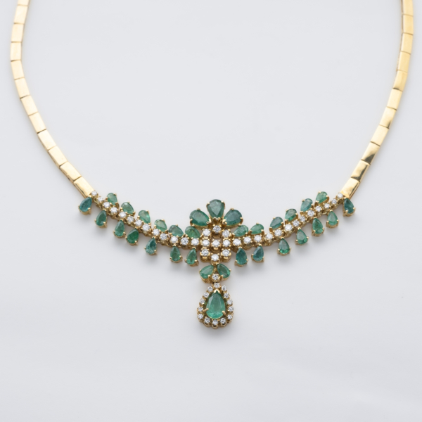 Gargantilla de eslabones planos articulados en oro con un centro de esmeraldas talla perilla y diamantes talla brillante engastados en garras.