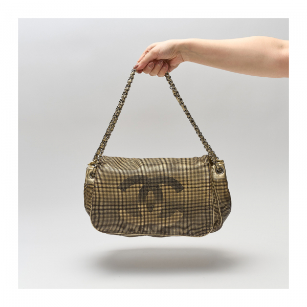 CHANEL. Bolso modelo «Hollywood Ombre» en cuero calado de acabado metalizado en dorado con logotipo central y cierre de solapa con botón imantado en interior.