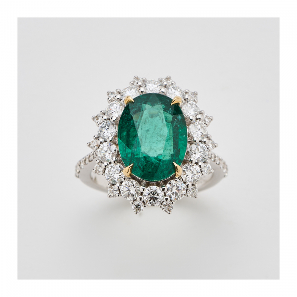 Sortija rosetón en oro blanco con esmeralda de Zambia talla oval y doble orla y brazos de diamantes talla brillante.