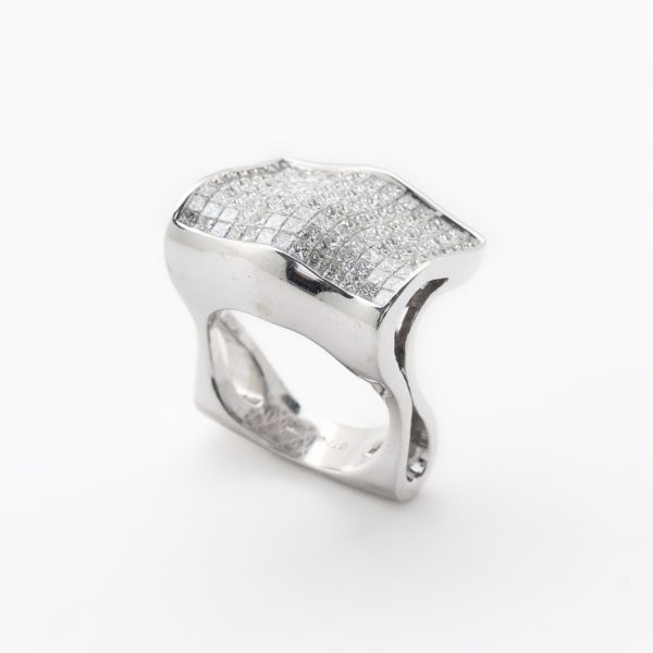 Sortija en oro blanco con frente rectangular ondulado cuajado de diamantes talla princesa engastados en invisible.