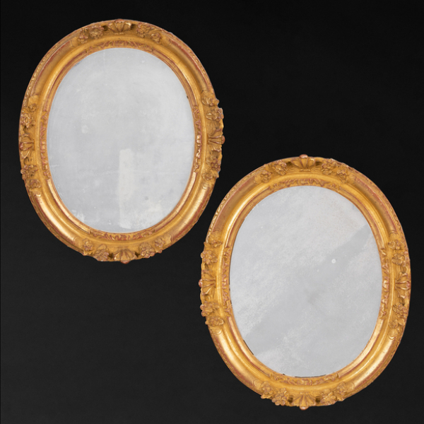 Pareja de espejos ovalados en madera tallada y dorada del siglo XX.