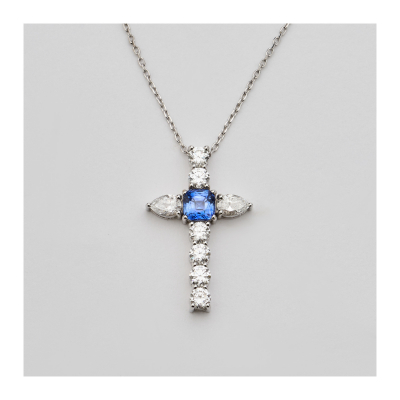 Cadena con colgante diseño cruz en oro blanco, zafiro azul talla cojín y diamantes tallas brillante y perilla.