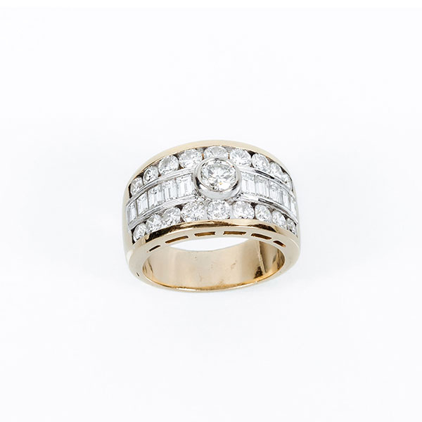 Sortija de alta joyería en sólida montura de oro amarillo con un limpio y blanco diamante talla brillante central sobre banda y filas de limpios y blancos diamantes talla baguette y brillante