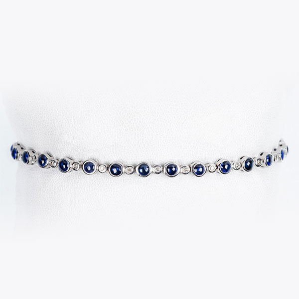 Bonita pulsera tipo 'rivière' en oro blanco 18 K, con zafiros finos azules, alternados por limpios y blancos diamantitos talla brillante