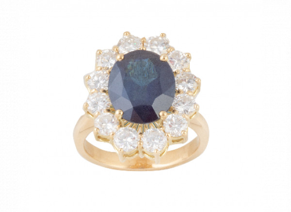 Sortija con zafiro oval de 6,33 ct. orlado de brillantes engastados en garras.   En montura de oro amarillo de 18K.