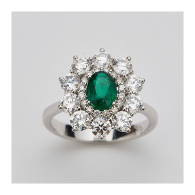 Sortija rosetón en oro blanco con esmeralda colombiana talla oval y doble orla de diamantes talla brillante.