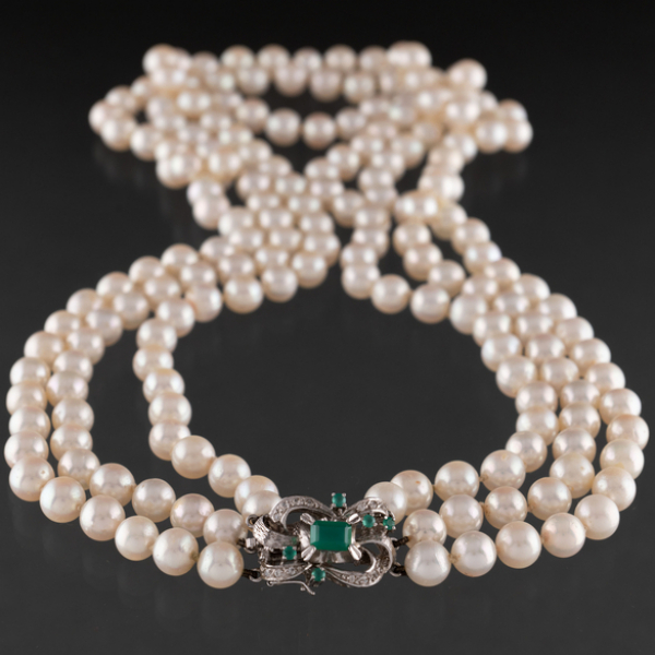 Elegante collar de perlas cultivadas de tres hilos con cierre en oro blanco y esmeraldas.