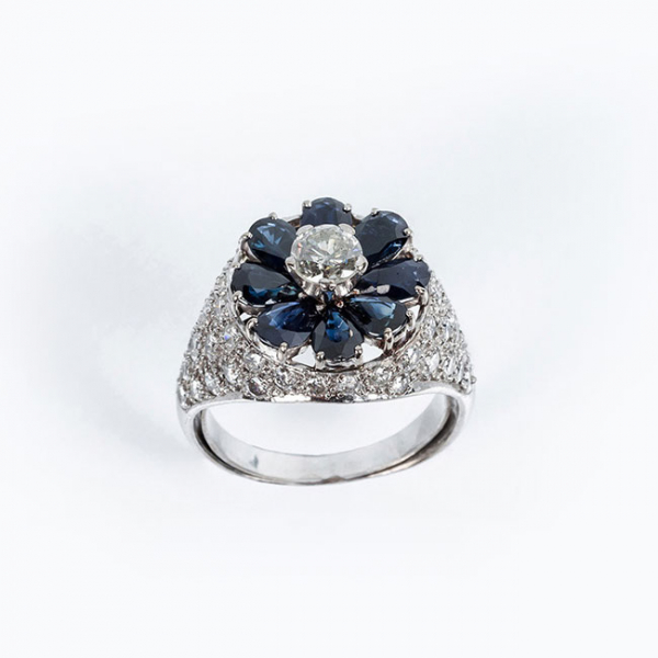 Sortija vintage de alta joyer&iacute;a en oro blanco 18 K, con un diamante natural central, talla brillante, sobre motivo en roset&oacute;n de zafiros finos azules 