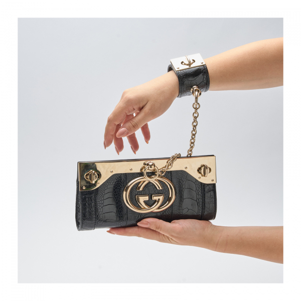 GUCCI. Bolso de mano modelo «Britt Bag» en piel de pata de vestruz negra con brazalete y cadena en metal dorado. En perfecto estado.