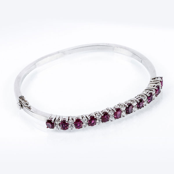 Brazalete esclavo vintage de alta joyería, en sólida montura de oro blanco 18 K, con motivo en fila de bellos rubíes naturales de intenso color, talla oval, alternados con pares de limpios y blancos diamantes naturales 