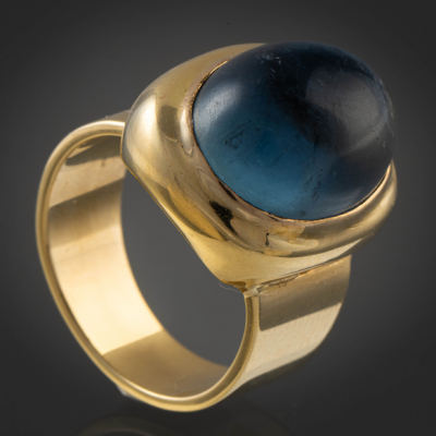 Anillo en oro amarillo de 18kt con piedra central color azul en cabuj&oacute;n.