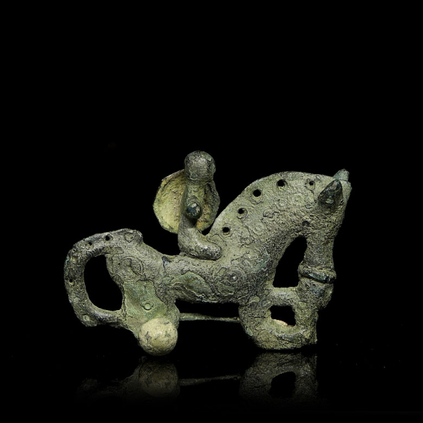 Edad del Hierro (s.III - II a.C) “Fíbula de jinete a caballo con escudo".    Objeto de bronce fundido 