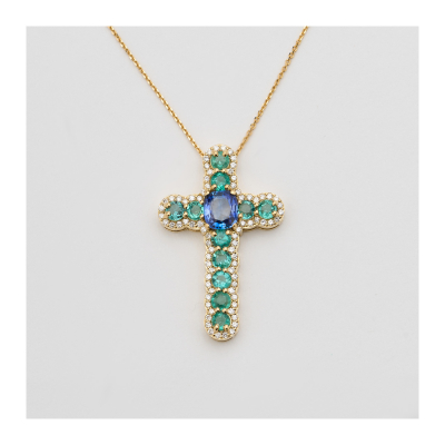 Cadena con colgante diseño cruz en oro, diamantes talla brillante, esmeraldas talla redonda y zafiro azul talla cojín engastados en garras.