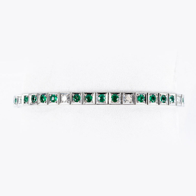 Pulsera riviere vintage en sólida montura de oro blanco 18 K, con fila articulada de esmeralditas en tramos alternados con limpios y blancos diamantes, talla brillante