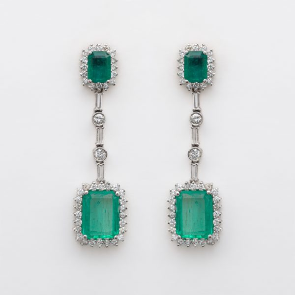 Pendientes largos en oro blanco con dos rosetones y barrita de diamantes tallas brillante y baguette y esmeraldas talla octogonal engastados en garras.