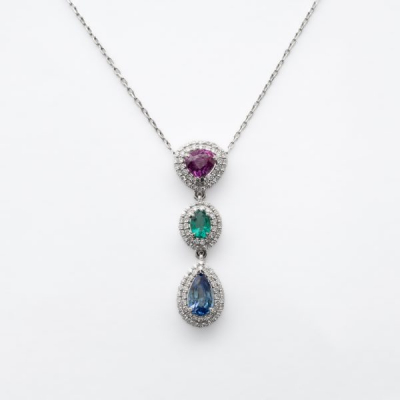 Gargantilla en oro blanco con tres rosetones de rub&iacute; talla trill&oacute;n, esmeralda talla oval y zafiro azul talla perilla orlados por dos bandas de diamantes talla brillante.