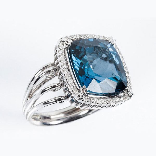 Sortija en montura calada de oro blanco 18 K, con un topacio azul 'London' cuadrangular, en garras, y orla en fila de limpios y blancos diamantes talla brillante