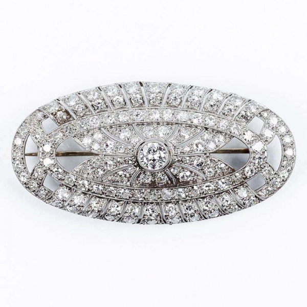 Bello broche antiguo 'art-decó' en montura oval de oro blanco, con un blanco diamante central, talla brillante