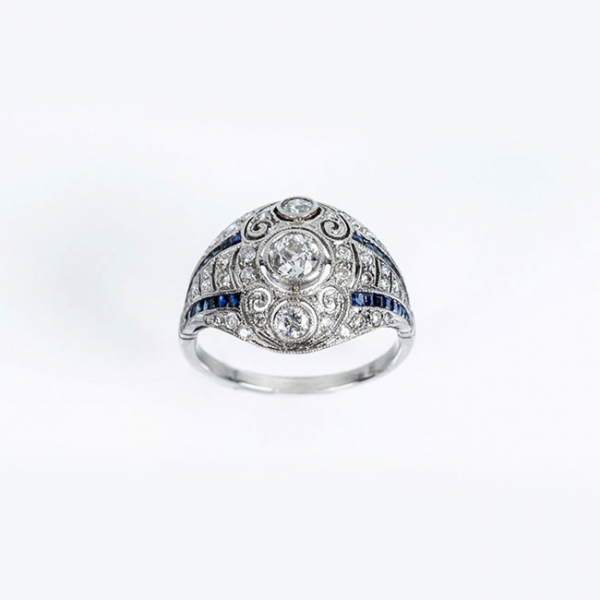 Delicada sortija estilo art-decó en platino, con un limpio y blanco diamante central y bandas de zafiros finos azules 