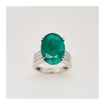 Sortija en oro blanco con esmeralda central talla oval y brazos de diamantes talla brillante.