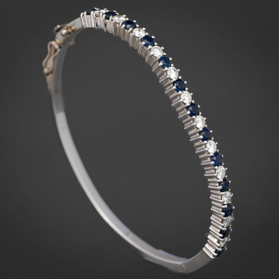 Pulsera rígida en oro blanco de 18kt con frontal orlado de brillantes y zafiros.