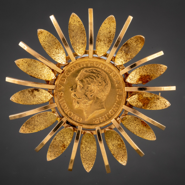Broche en forma de sol en oro amarillo de 18 kt con moneda de George V en el interior.