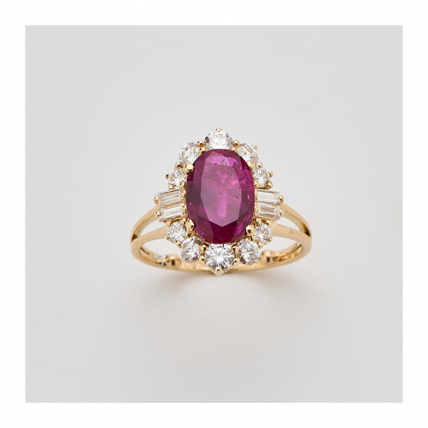 Sortija rosetón en oro con rubí de Burma talla oval orlado y custodiado por diamantes tallas brillante y baguette.