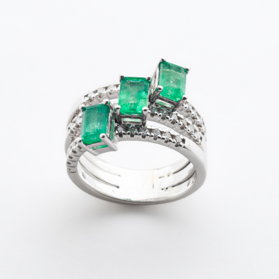 Sortija en oro blanco con tres esmeraldas rectangulares y brazos de pav&eacute; de diamantes talla brillante. 