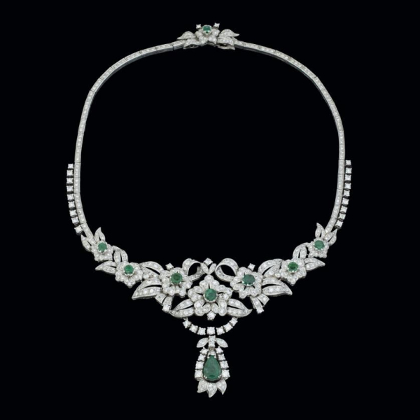 Collar de oro blanco de 18 K. con una esmeralda talla pera y siete talla redonda sobre secciones en forma de flor y cintas curvas cuajadas de diamantes.