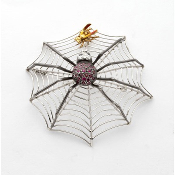 Broche en oro blanco en forma de telaraña con cuerpo de araña cuajado de granates y cabeza con diamantes blancos y negros