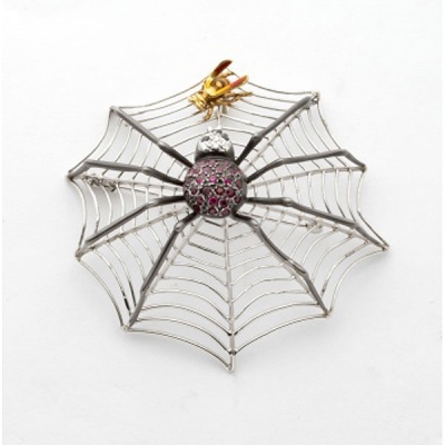 Broche en oro blanco en forma de telaraña con cuerpo de araña cuajado de granates y cabeza con diamantes blancos y negros