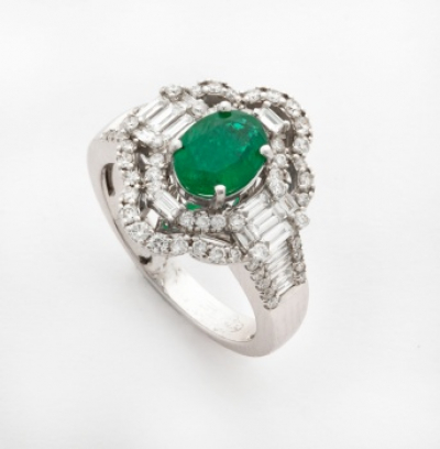 Sortija en oro blanco con esmeralda central, 2 orlas de diamantes talla brillante y diamantes talla baguette en el brazo
