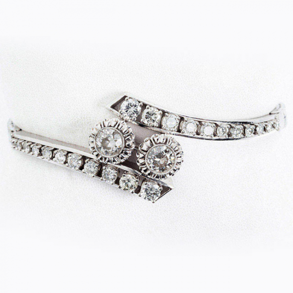 Brazalete vintage en oro blanco 18 K, con motivo central de dos limpios y blancos diamantes, talla brillante en chatón grafilado con garras de ilusión, flanqueados por bandas de limpios y blancos diamantes 