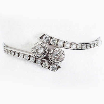 Brazalete vintage en oro blanco 18 K, con motivo central de dos limpios y blancos diamantes, talla brillante en chatón grafilado con garras de ilusión, flanqueados por bandas de limpios y blancos diamantes 