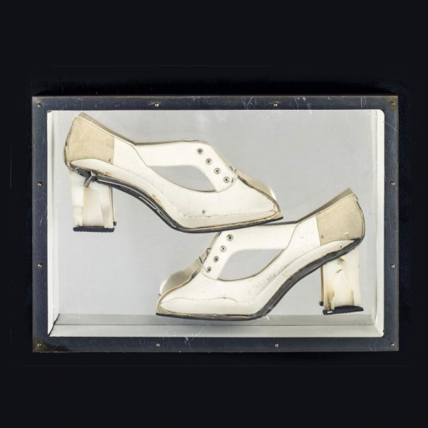Arman.   "Construction of shoes (1965)". Zapato de tacón (coupe) sobre panel de madera negra con cubierta de plexiglás.