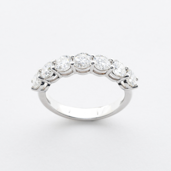 Sortija media alianza en oro blanco con diamantes talla brillante engastados en garras.  
