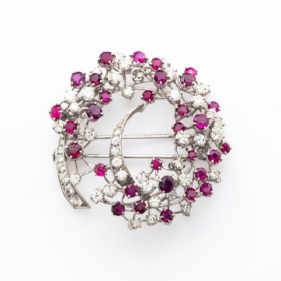 Broche calado estilo corona floral en oro blanco cuajado de diamantes talla brillante y rub&iacute;es talla redonda engastados en garras.