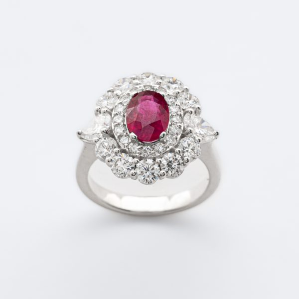 Sortija rosetón en oro blanco con rubí (Burma) talla oval y doble orla de diamantes talla brillante custodiados por diamantes talla trillón.