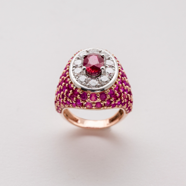 Sortija sello en oro rosa y blanco con cuerpo cuajado de rub&iacute;es talla redonda y roset&oacute;n central con rub&iacute; talla oval orlado por diamantes talla brillante.